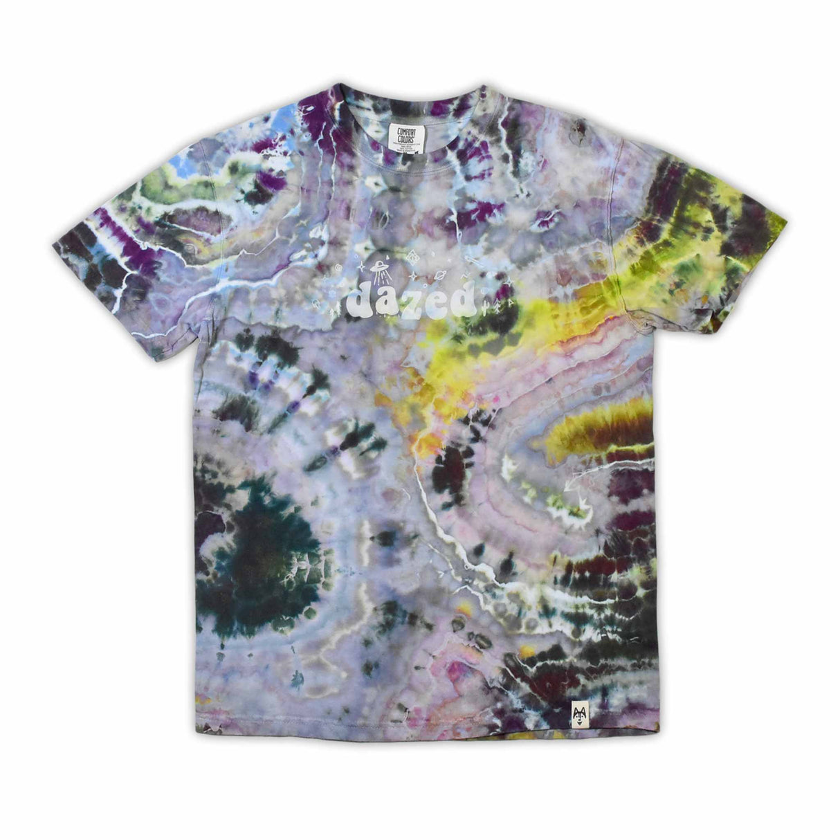 An artisanal ice-dyed t-shirt, its surface a canvas of swirling blues, purples, and chartreuse resembling geode formations, with the text 'dazed' in a stylized, icy lettering at the center.