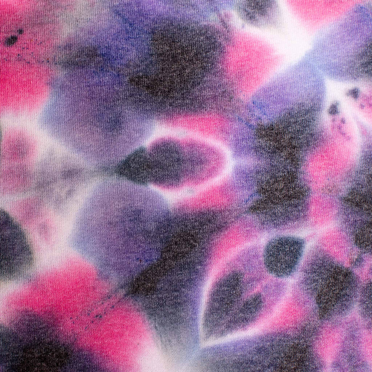 These soft sweatpants exhibit a tie-dye design with splashes of magenta and lavender, contrasted by patches of inky black.