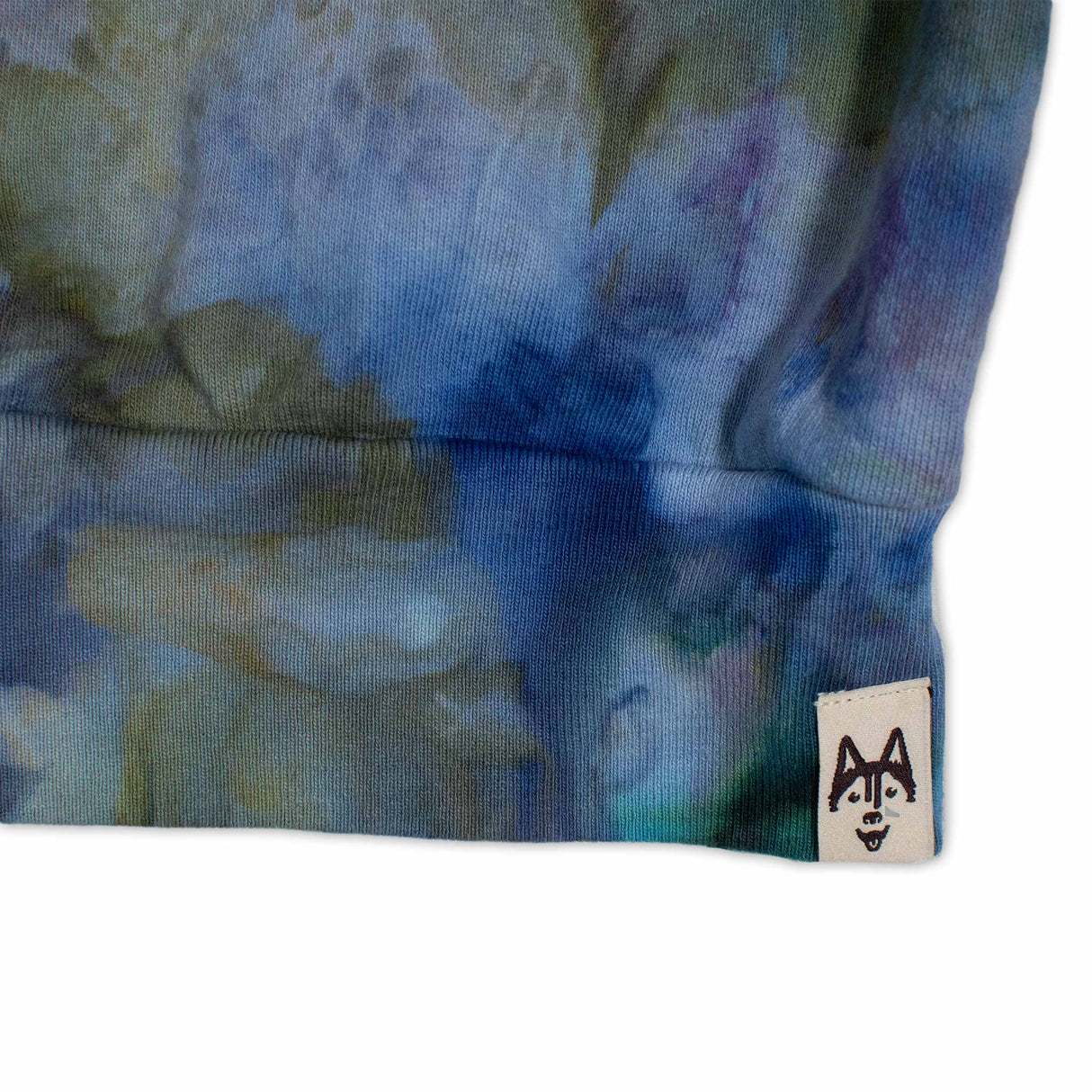 A cozy sweatshirt showcases an ice dye technique with a fusion of deep blues and soft greens, inviting a sense of calm and comfort."