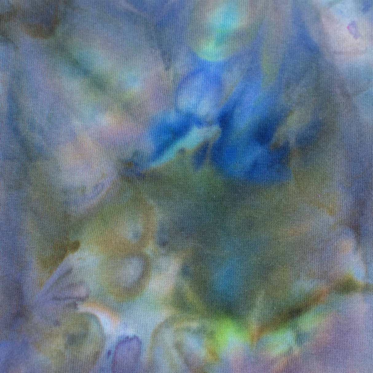 A cozy sweatshirt showcases an ice dye technique with a fusion of deep blues and soft greens, inviting a sense of calm and comfort."